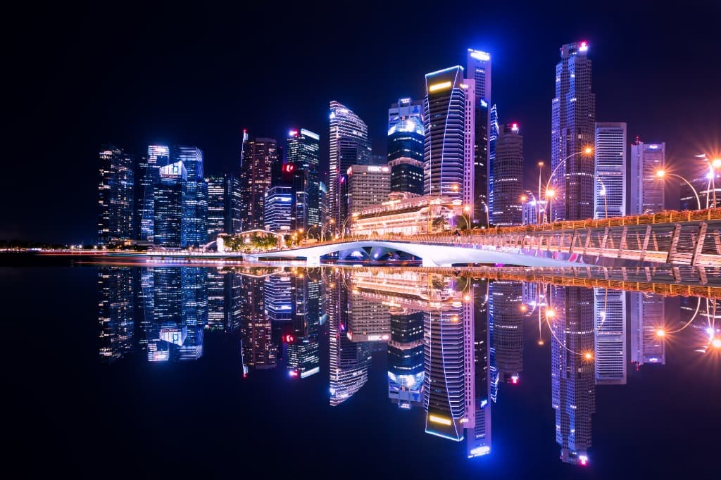 Singapore city skyline at night, illuminated skyscrapers reflected in Marina Bay